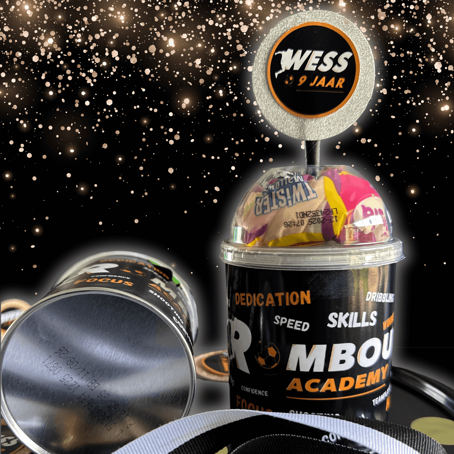 Personalized traktatie cup with Rombout Academy branding, transparent lid full of candy, and custom medal with name and age.